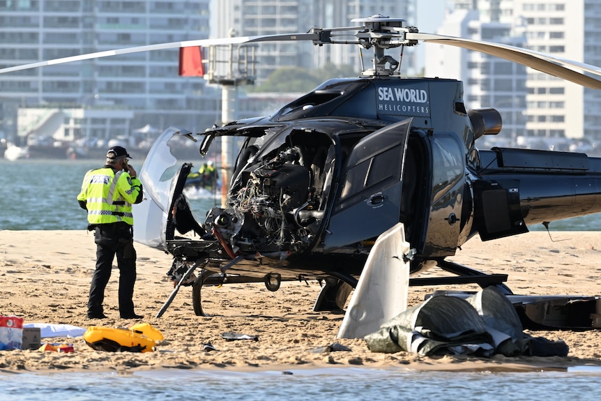 A damaged helicopter on a sandbank.