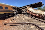 A train which has been smashed and derailed sitting across train tracks
