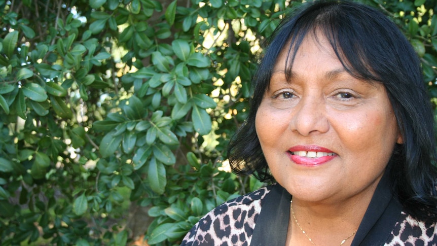 Rhonda Collard-Spratt smiling and standing in front of a green hedge