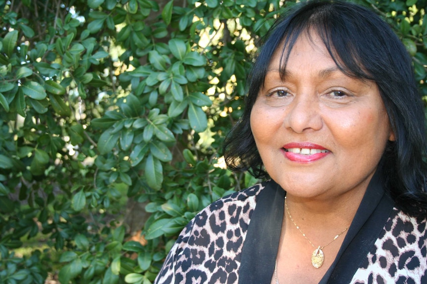 Rhonda Collard-Spratt smiling and standing in front of a green hedge