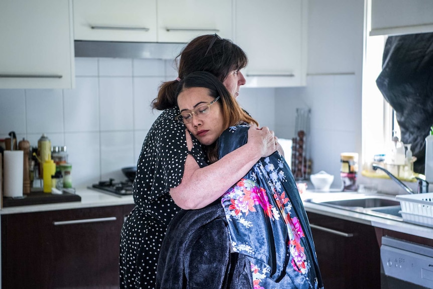 Mother Anne* and grandmother Susan* embrace in the kitchen