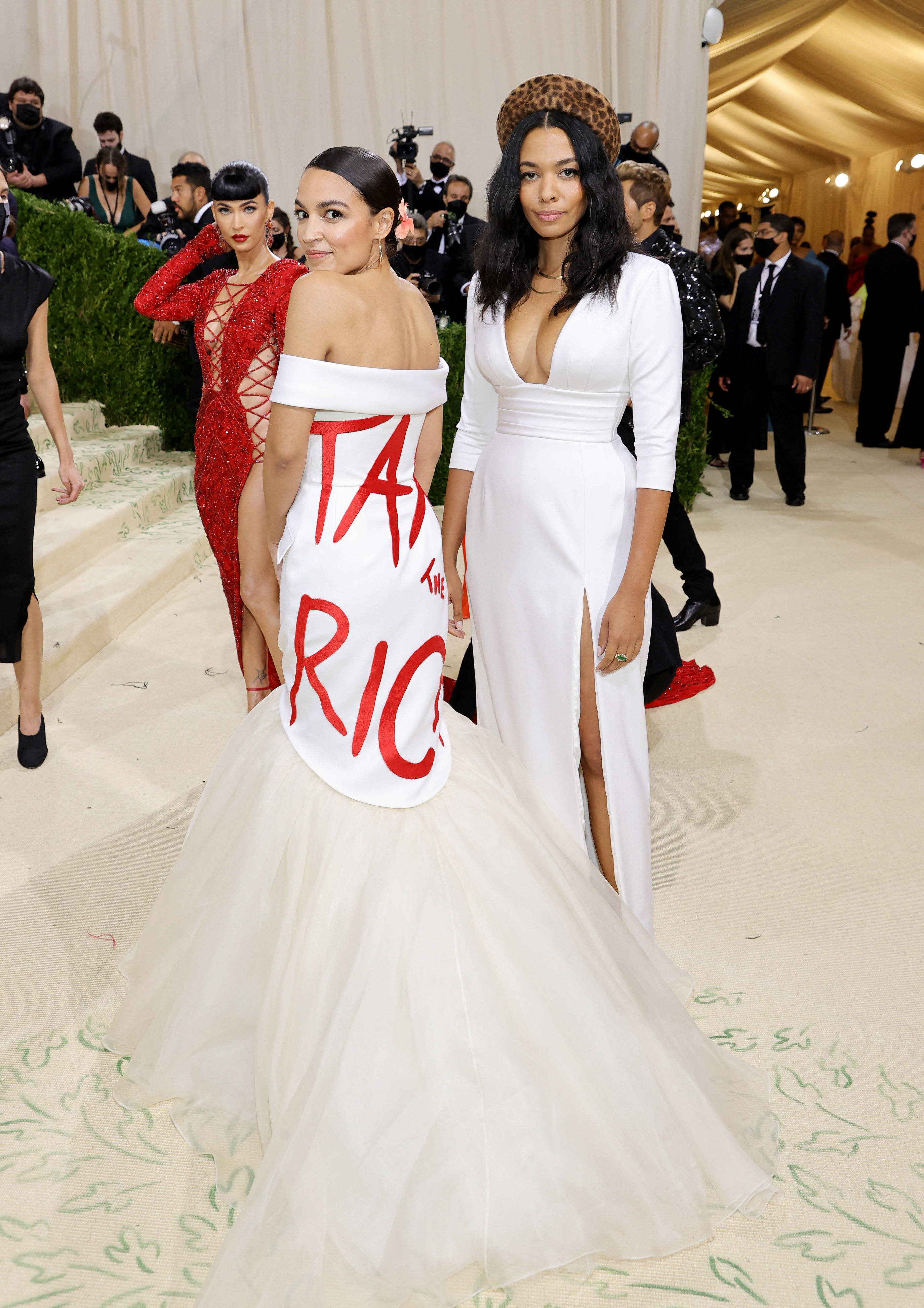 Alexandria Ocasio-Cortez wears a white floor length dress with "Tax the Rich" written in red letters.