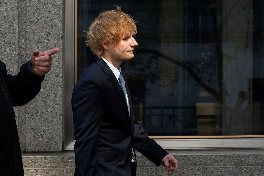 Ed Sheeran wears a dark blue suit as he walks