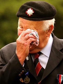 Veteran presents the flag of his country at a ceremony honouring the efforts of Allied forces during the D-day landings.