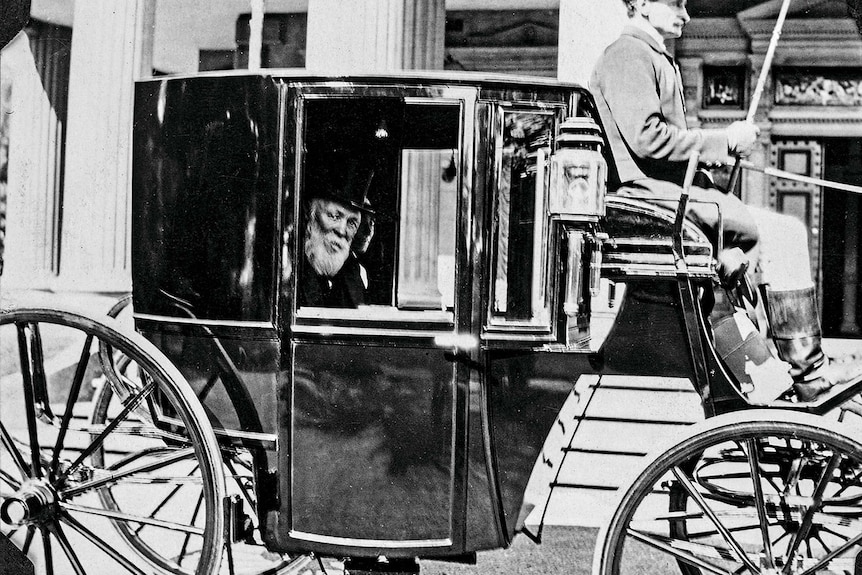 Black and white photo of an older man in a horse-drawn carriage on Bourke Street.
