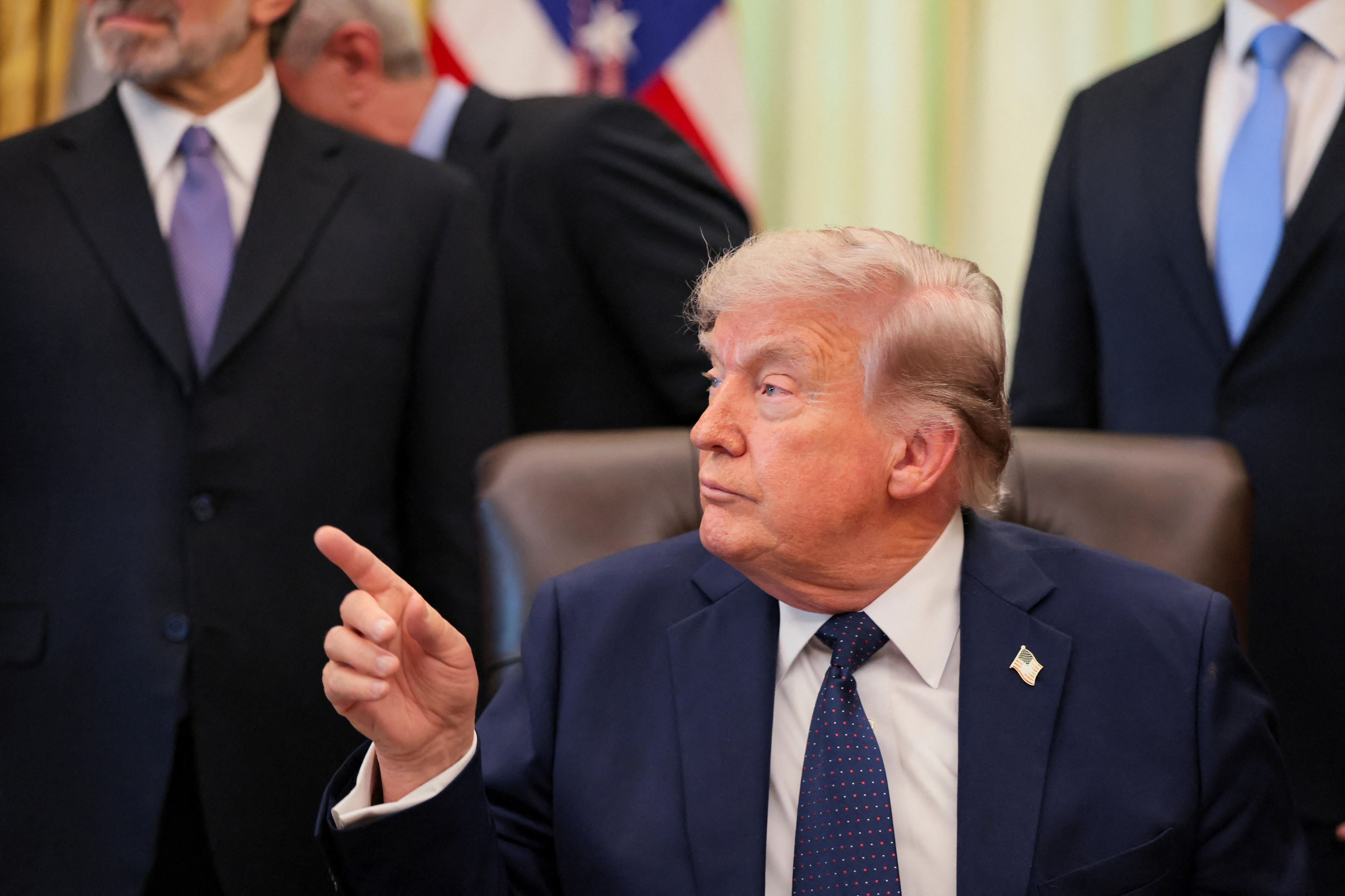 donald trump points his finger at a colleague, he is sat down and dressed in a navy suit