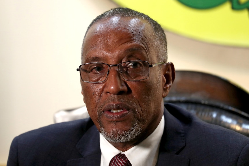 A close up shot of a man wearing a suit and glasses. 