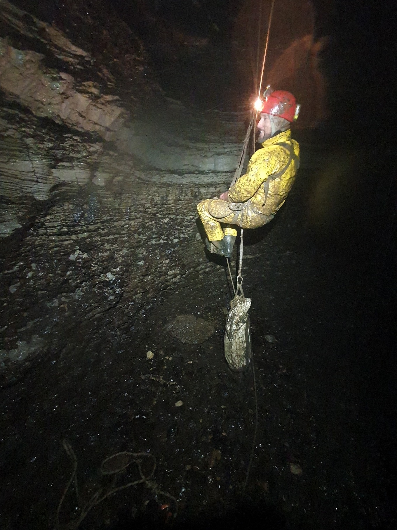 A man abseils down into a dark abyss.