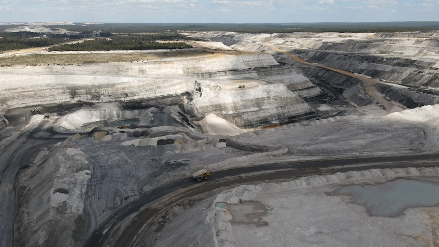 A truck moves across an open cut mine