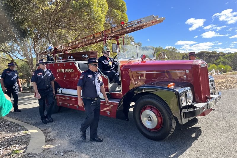 vintage red fire truck with four men walking