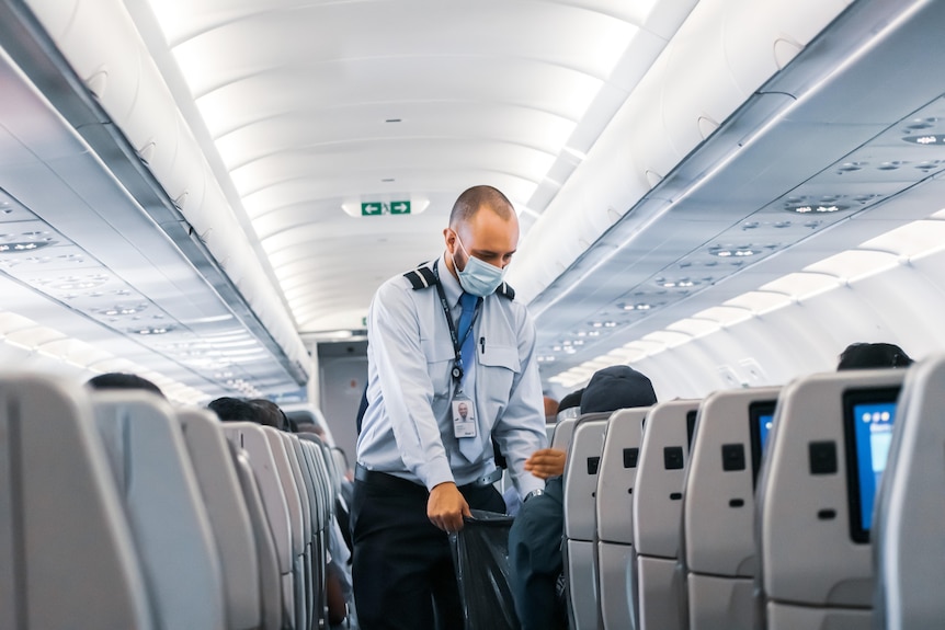 Image of a person with a mask cleaning the inside of a plane. 