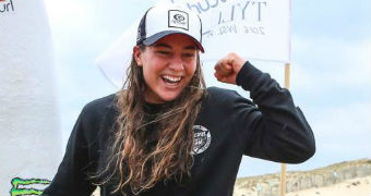 Tyler Wright pumps her fist in the air as she celebrates her surfing world title.
