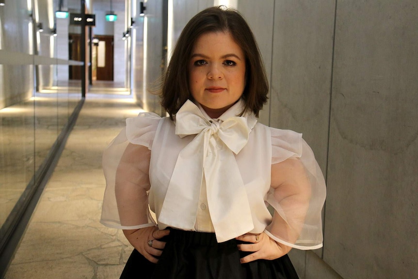 Sinead Burke stands with her hands on her hips in a hallway in a building in Brisbane in October 2019