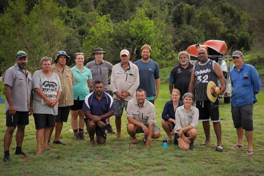 A group of traditional owners and scientists standing in a grassy field.
