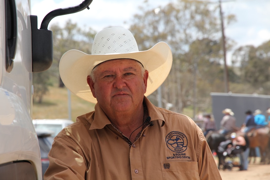 A man in a cowboy hat leans against a truck.