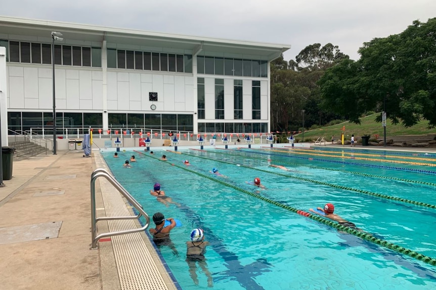 Los nadadores usan sombreros de eneldo en los pasillos de la piscina al aire libre.