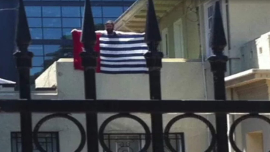 Still from a video showing a man protesting at the Indonesian consulate in Melbourne. He is holding a West Papua flag.