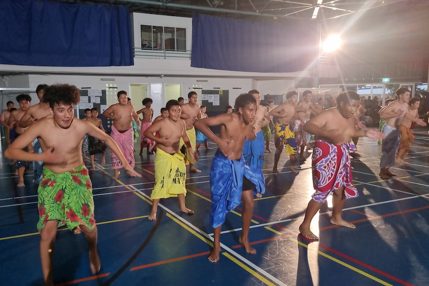 Rows of boys wearing ie lavalava practice the Samoan slap dance. 
