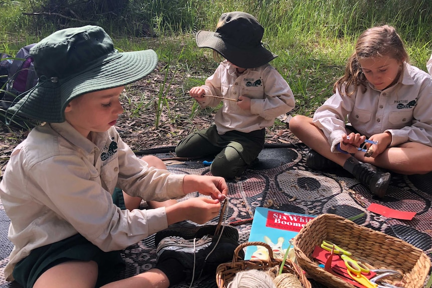 Students playing with wool on a mat.