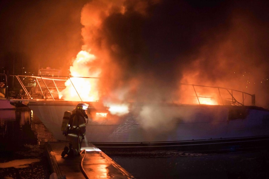 A firefighter approaches a boat fire in Hobart.