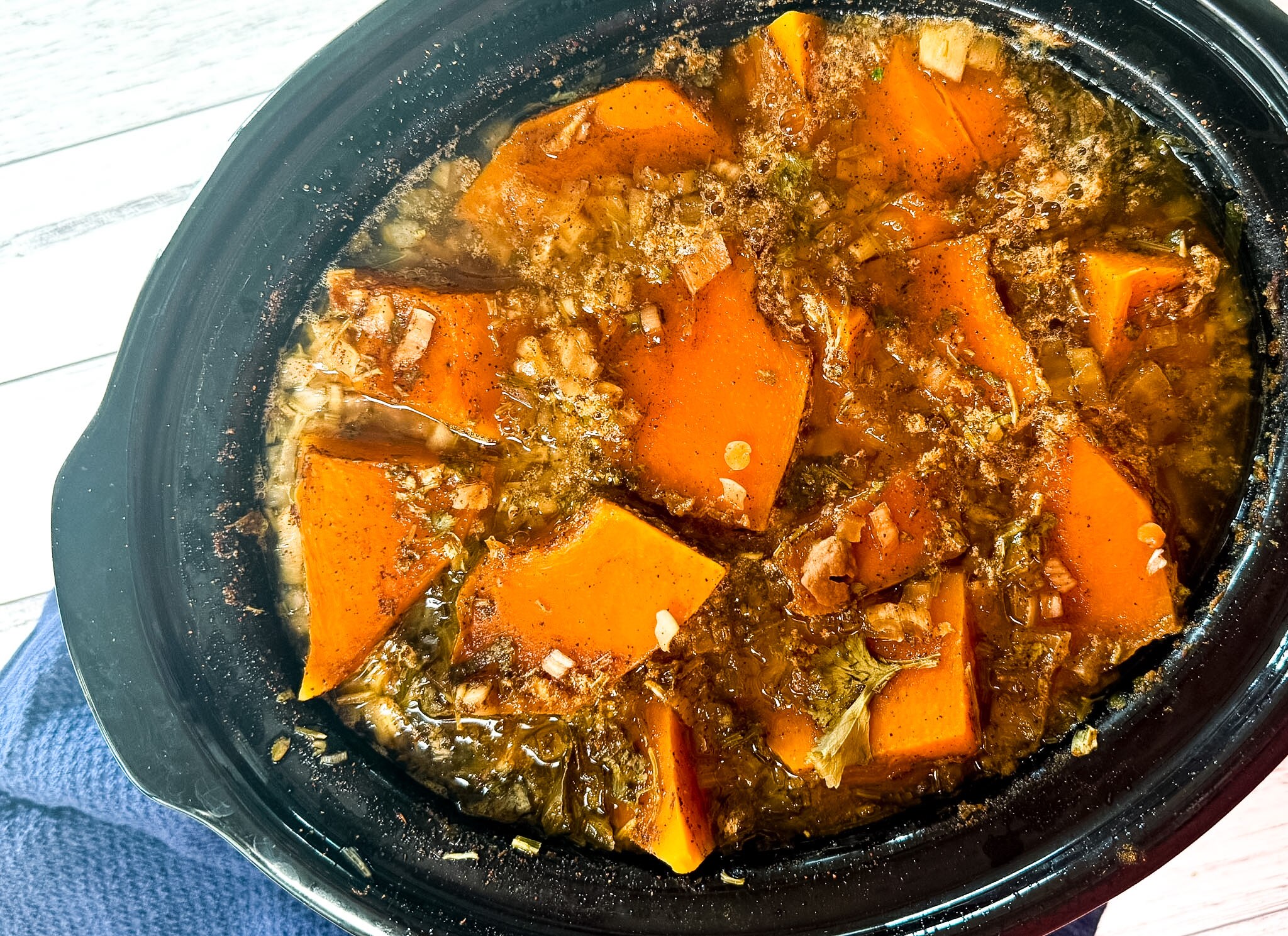 A slow cooker with chunks of pumpkin, spices, lentils and water, which will transform into a creamy curry.