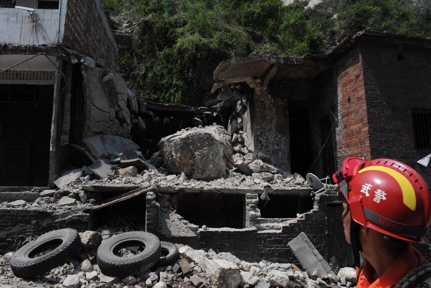 A rescuer looks at a damaged home in Yiliang after twin quakes in China