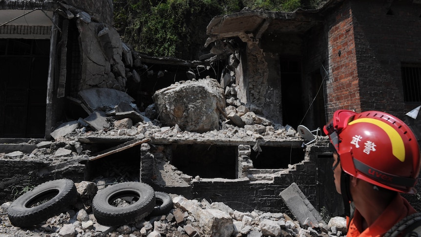 A rescuer looks at a damaged home in Yiliang after twin quakes in China