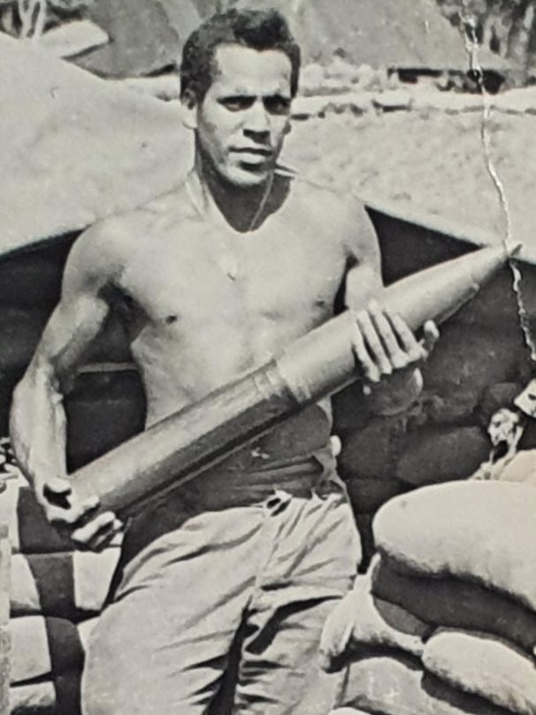 A black and white photo of a man sitting on a gun artillary.