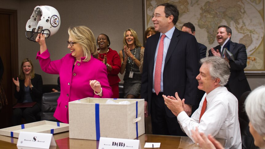 Hillary Clinton holds a football helmet she received after returning to work.