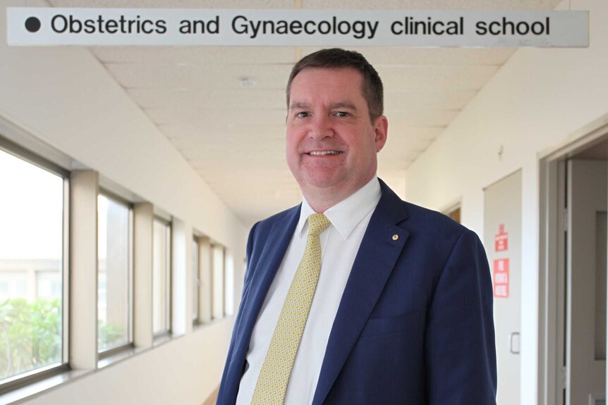 Obstetrician, Professor Euan Wallace stands in the hallway of Monash School of Obstetrics and Gynaecology