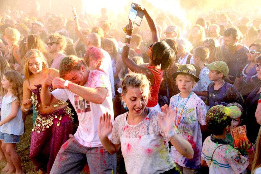 A crowd of people in colourful clothes dance.