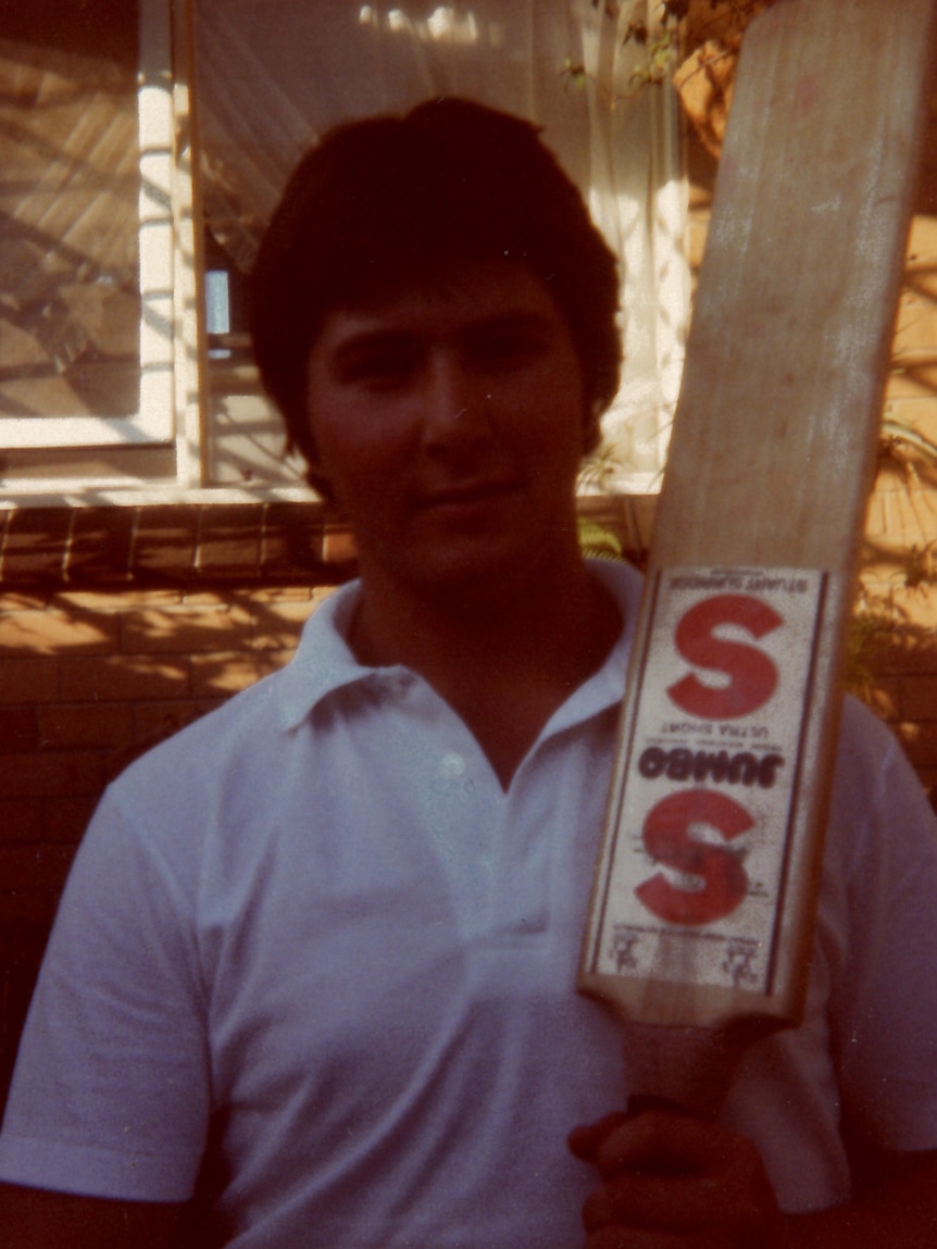 A young man holds a bat over his shoulder