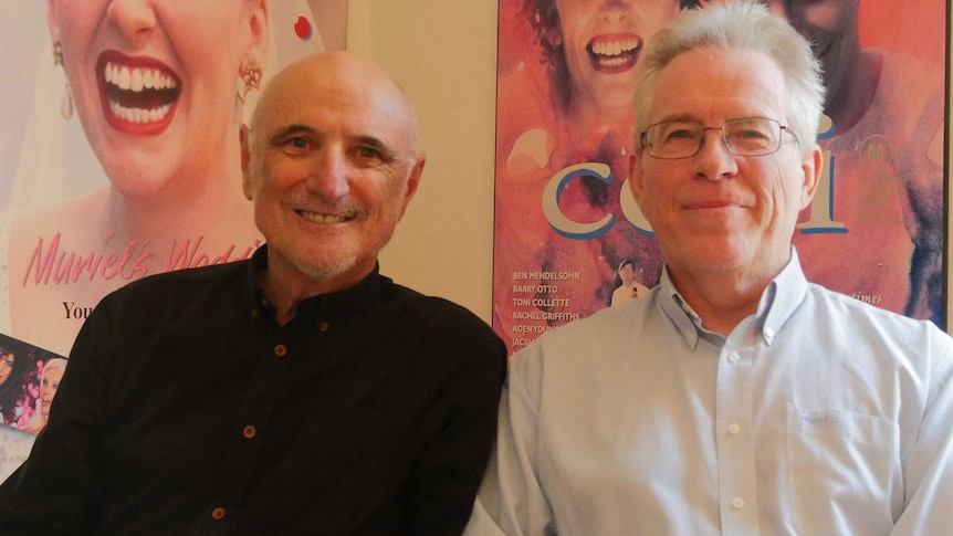 Ozflix founders Alan Finney and Ron Brown sitting in front of Australian movie posters
