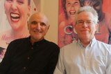 Ozflix founders Alan Finney and Ron Brown sitting in front of Australian movie posters