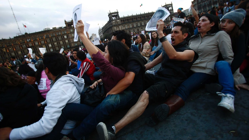 Demonstrators sit on the ground during a protest in support of the missing students at Zocalo square in Mexico City November 8, 2014.
