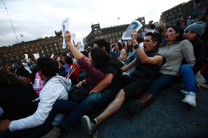 Demonstrators sit on the ground during a protest in support of the missing students at Zocalo square in Mexico City November 8, 2014.