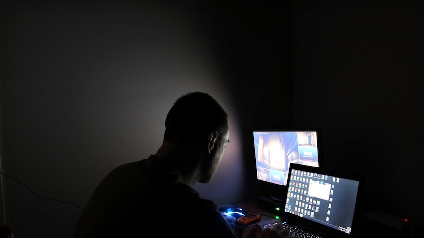 Man in a dark room looking at computers