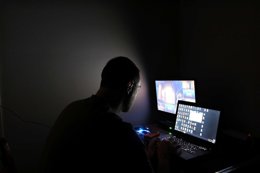 Man in a dark room looking at computers