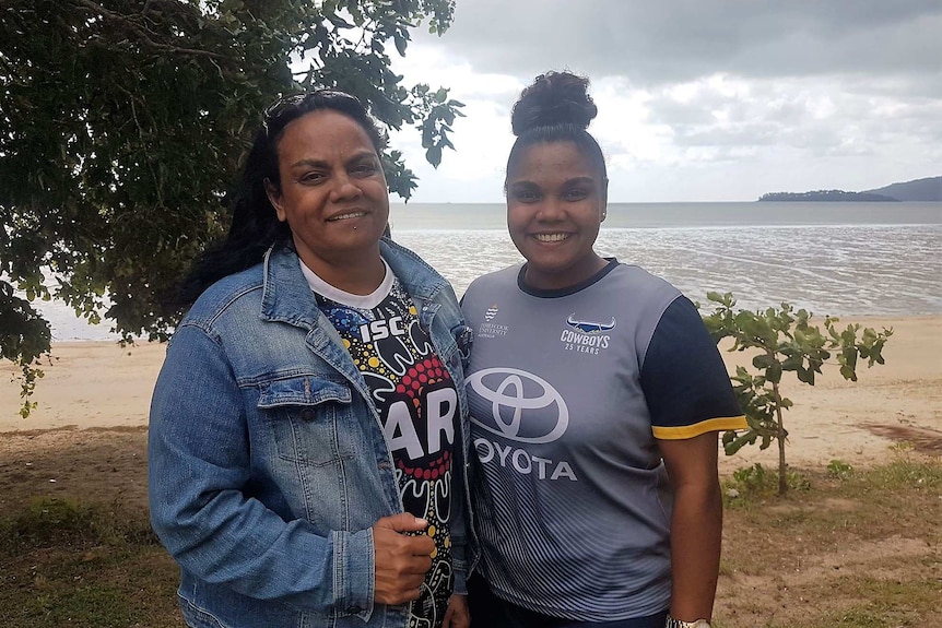 Aboriginal woman and teenage daughter standing on beach