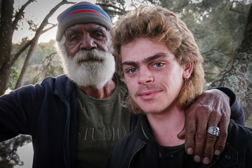 An Indigenous elder and his grandson looking at the camera