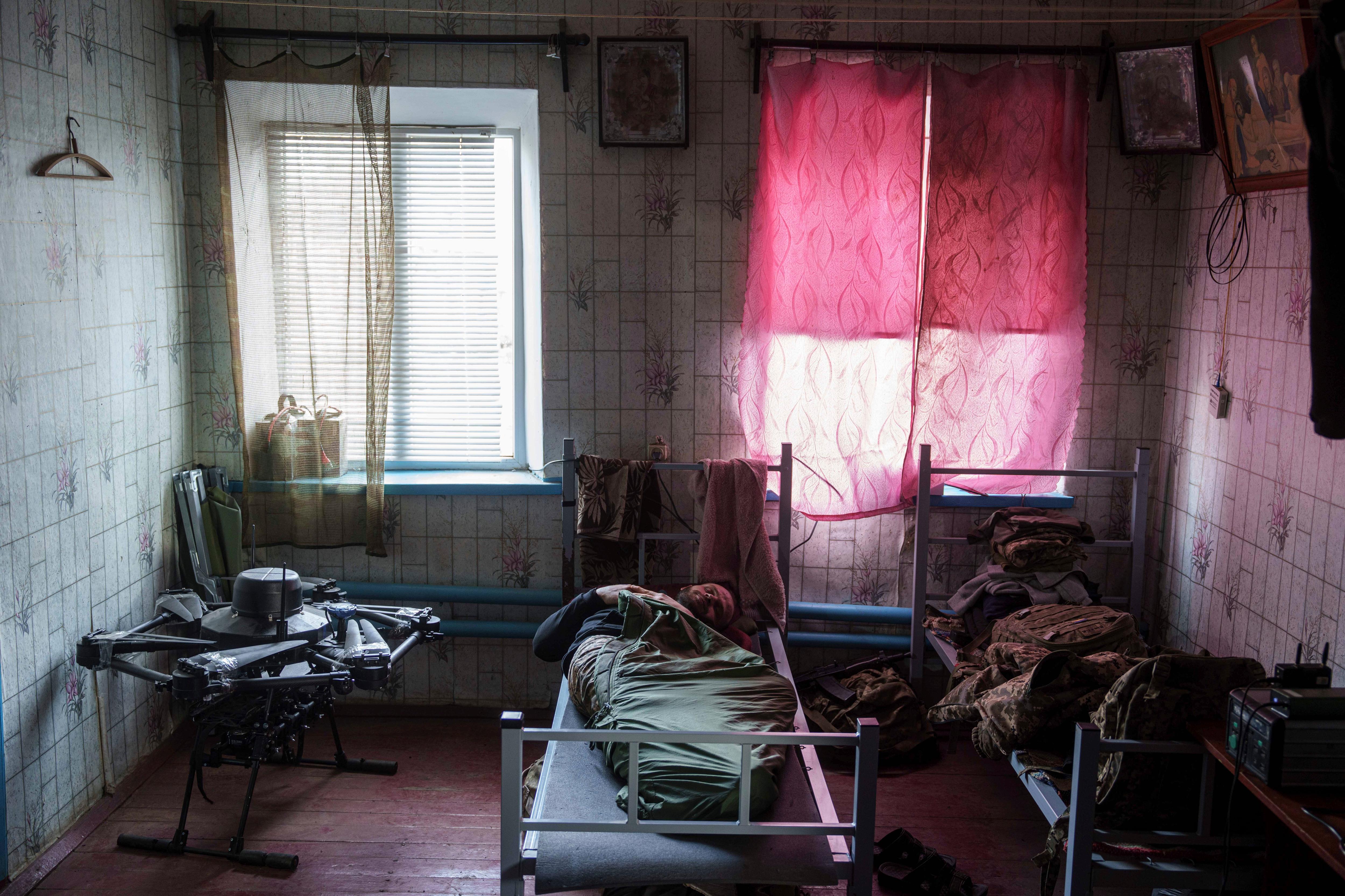A soldier rests on a cot bed in a small room.