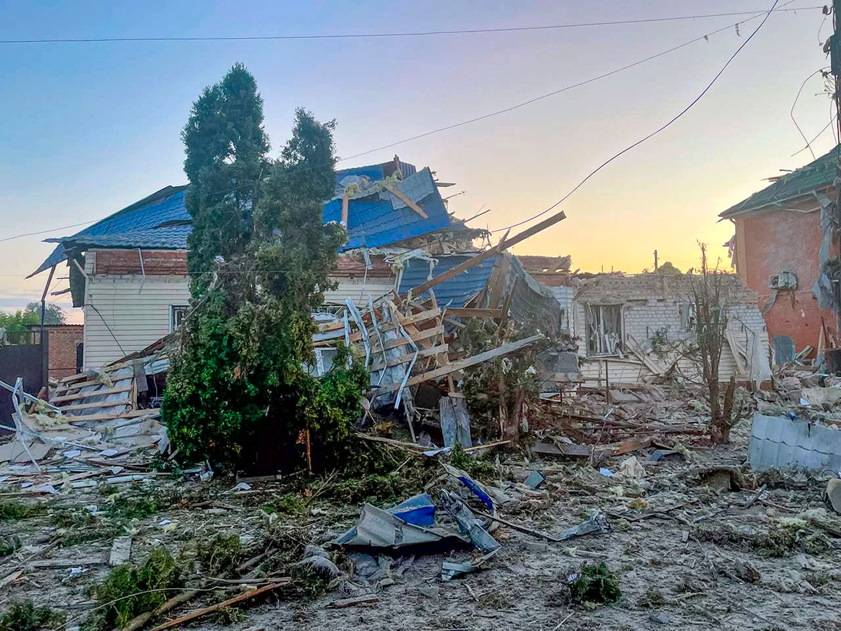 A house reduced to rubble, with a tree in front.