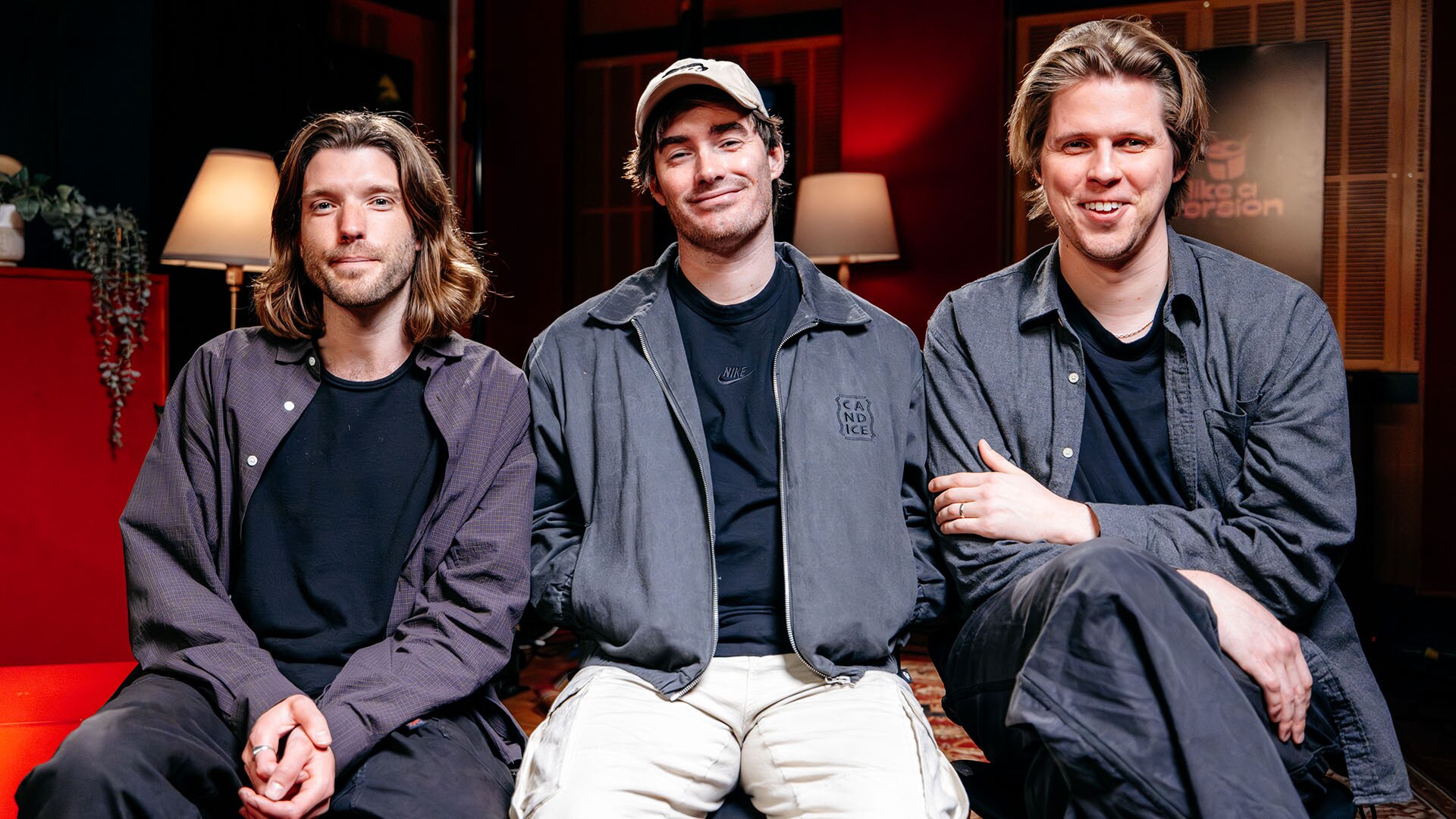 Three men sit in the LAV studio, facing the camera. They are all smiling.
