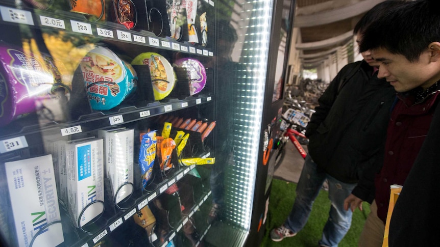 Students look at HIV testing kits in a vending machine.