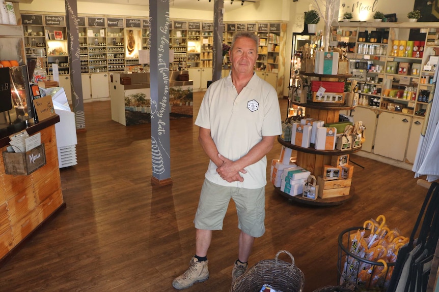 A man stands in the middle of a honey shop with no other people inside.