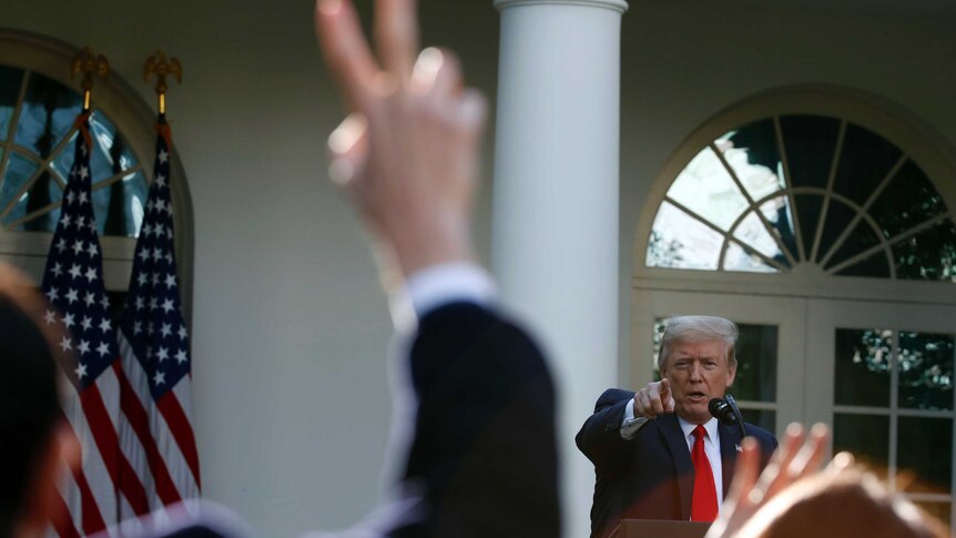 US President Donald Trump points to a reporter with a raised hand during a press conference
