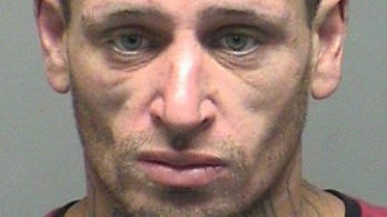 A man has a neutral expression in a mugshot. The word 'thug' is tattooed on his neck