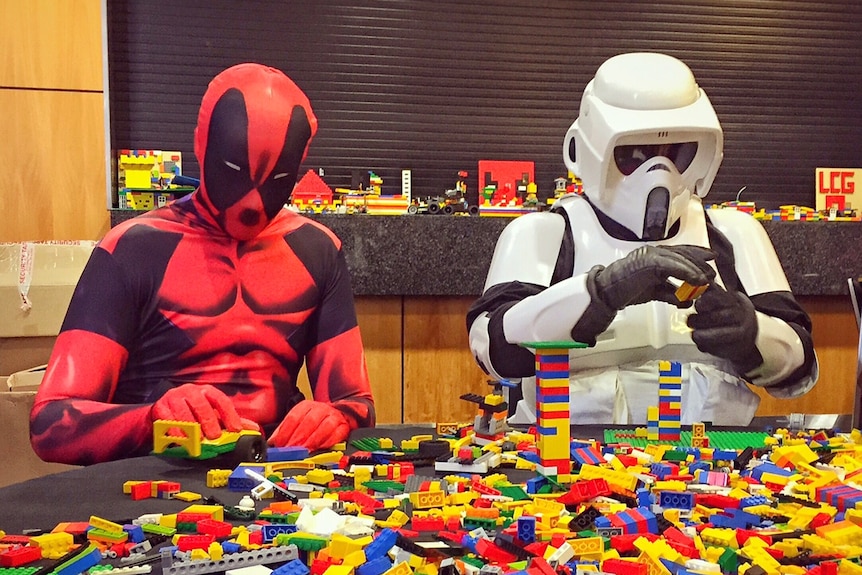 Men in costume build with Lego.