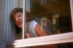A woman leans out a window with an expression like she's yelling at someone