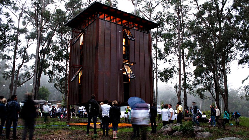 The copper clad exterior of the piano milll building among gum trees and surrounded by people.